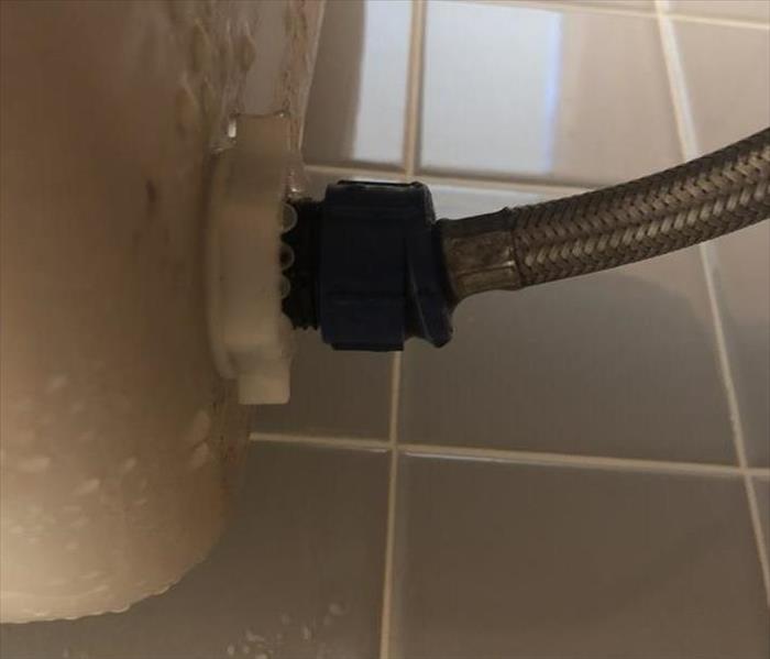 The back of a wet toilet is shown where a hose isn't fully connected