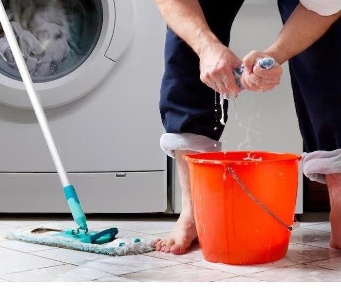 A person's hands are shown wringing out a towel into a bucket