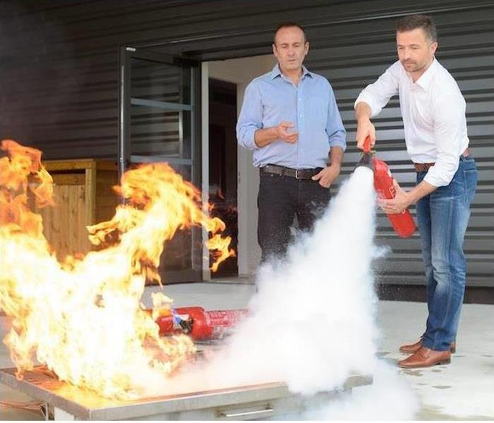 A man is shown putting out a fire with a fire extinguisher 
